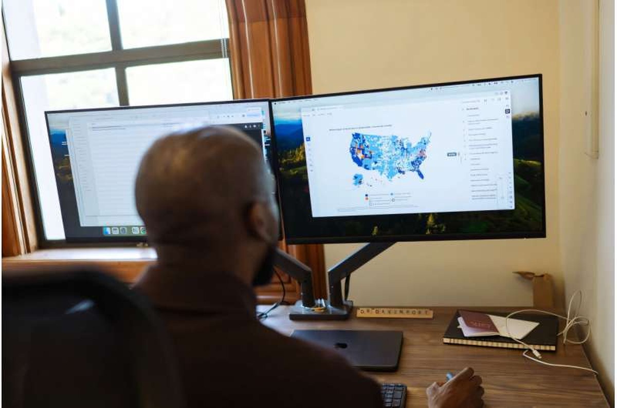 A view of Diag Davenport's shoulder as he scrolls on a computer screen across a map of the U.S. that contains different shades of blue.